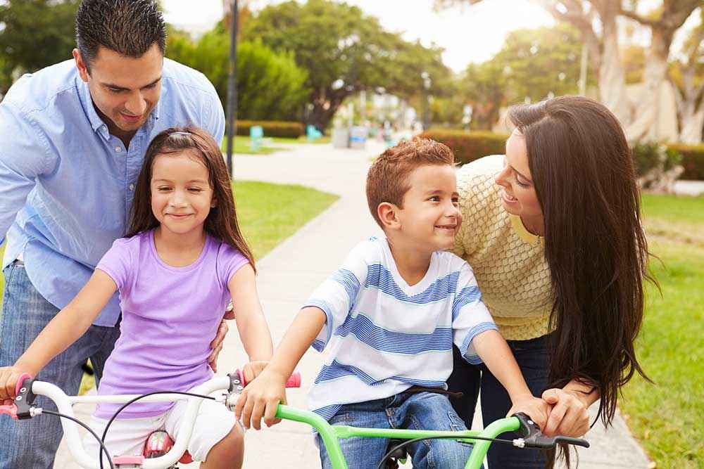 Family riding bikes together in park near Pico Rivera Collection